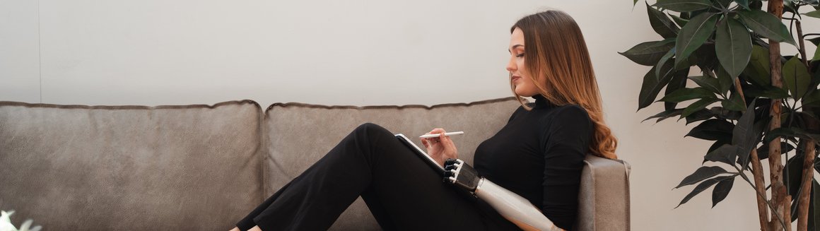 Frau sitzt mit Tablet auf der Couch