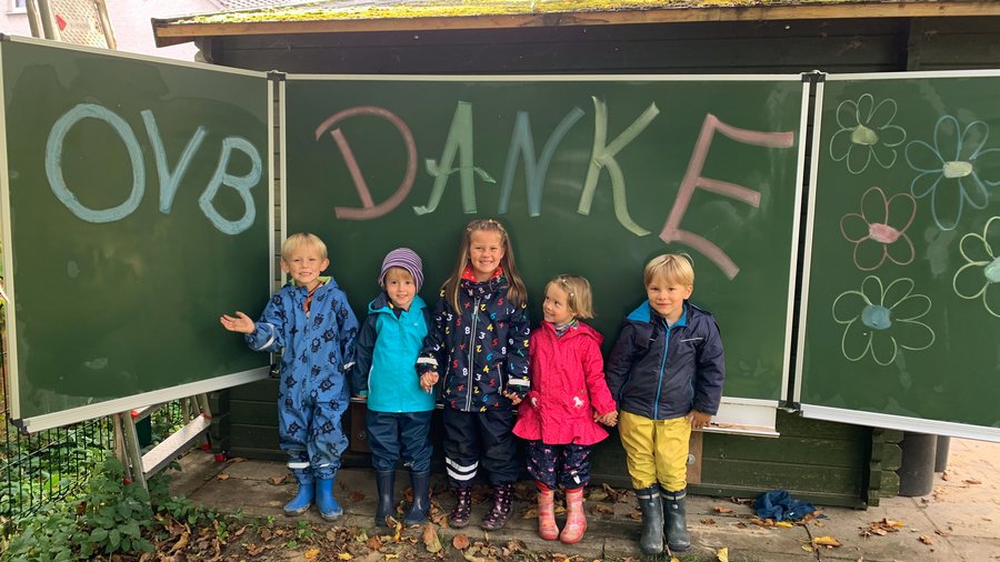 Fünf Kindergartenkinder stehen vor Tafel auf der Danke OVB steht
