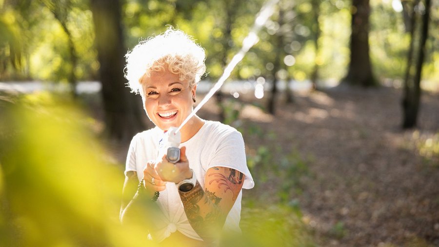 Lachende gesunde Frau mit Wasserpistole