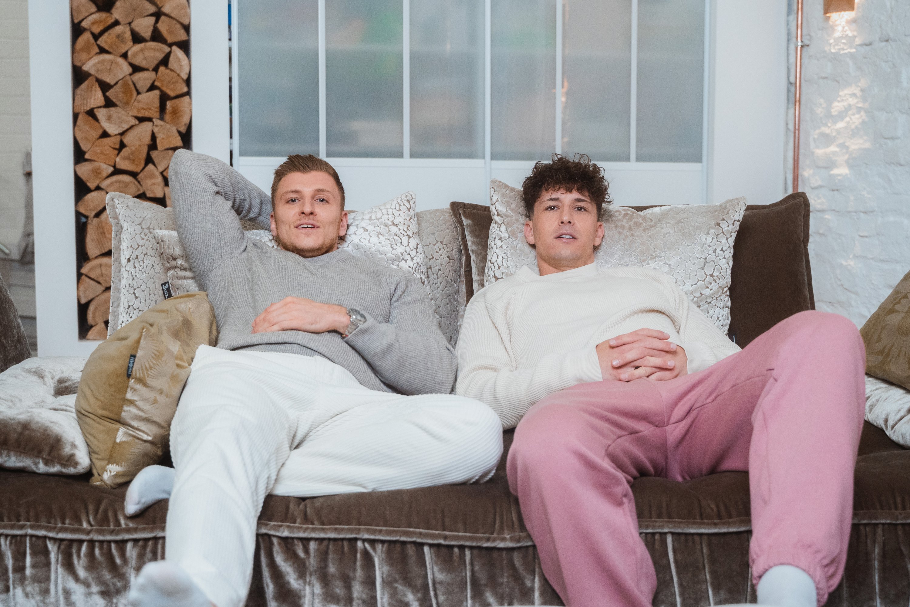 Zwei junge Männer sitzen auf einer Couch.