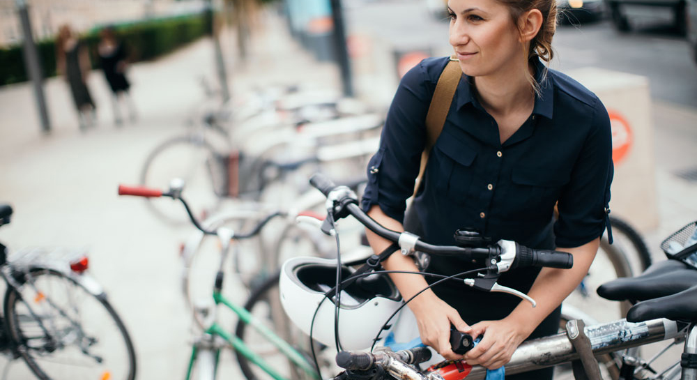 Fahrradversicherung: Frau schließt Fahrrad ab
