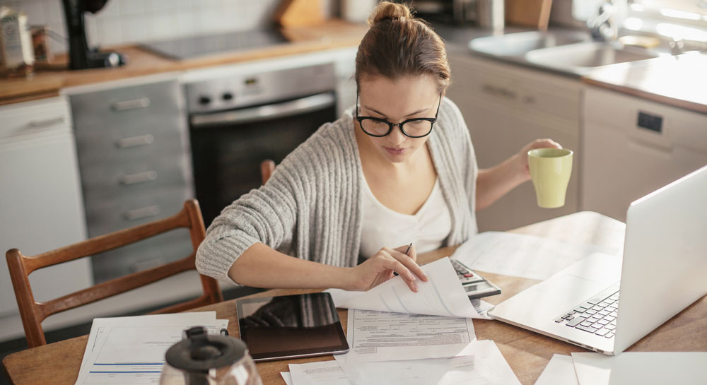 Bonitätsprüfung Schufa Bonitätsprüfung: Frau arbeitet konzentriert mit Unterlagen und Laptop