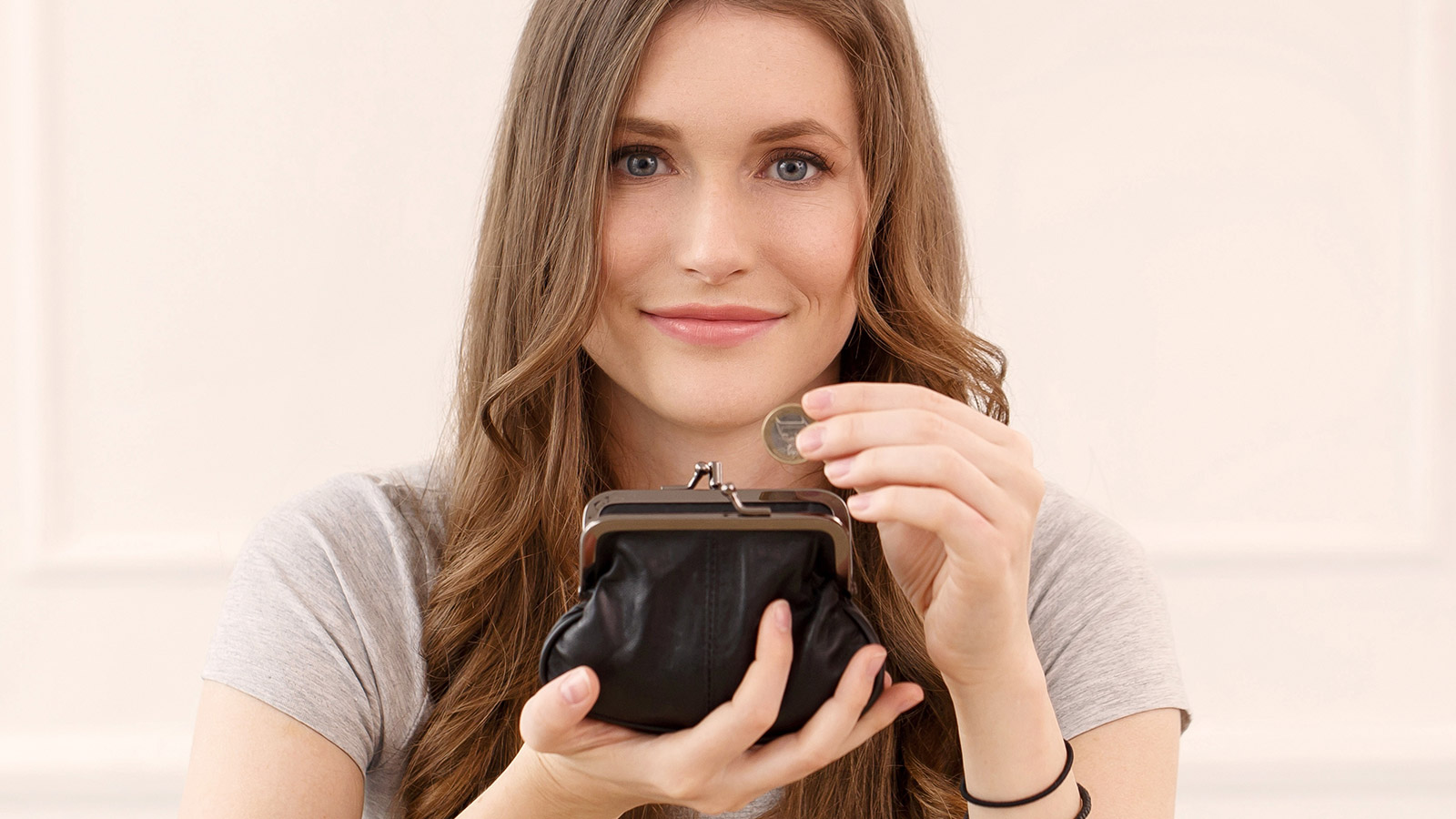 Eine Frau hält ein Portmonait mit Geldmünze in der Hand.