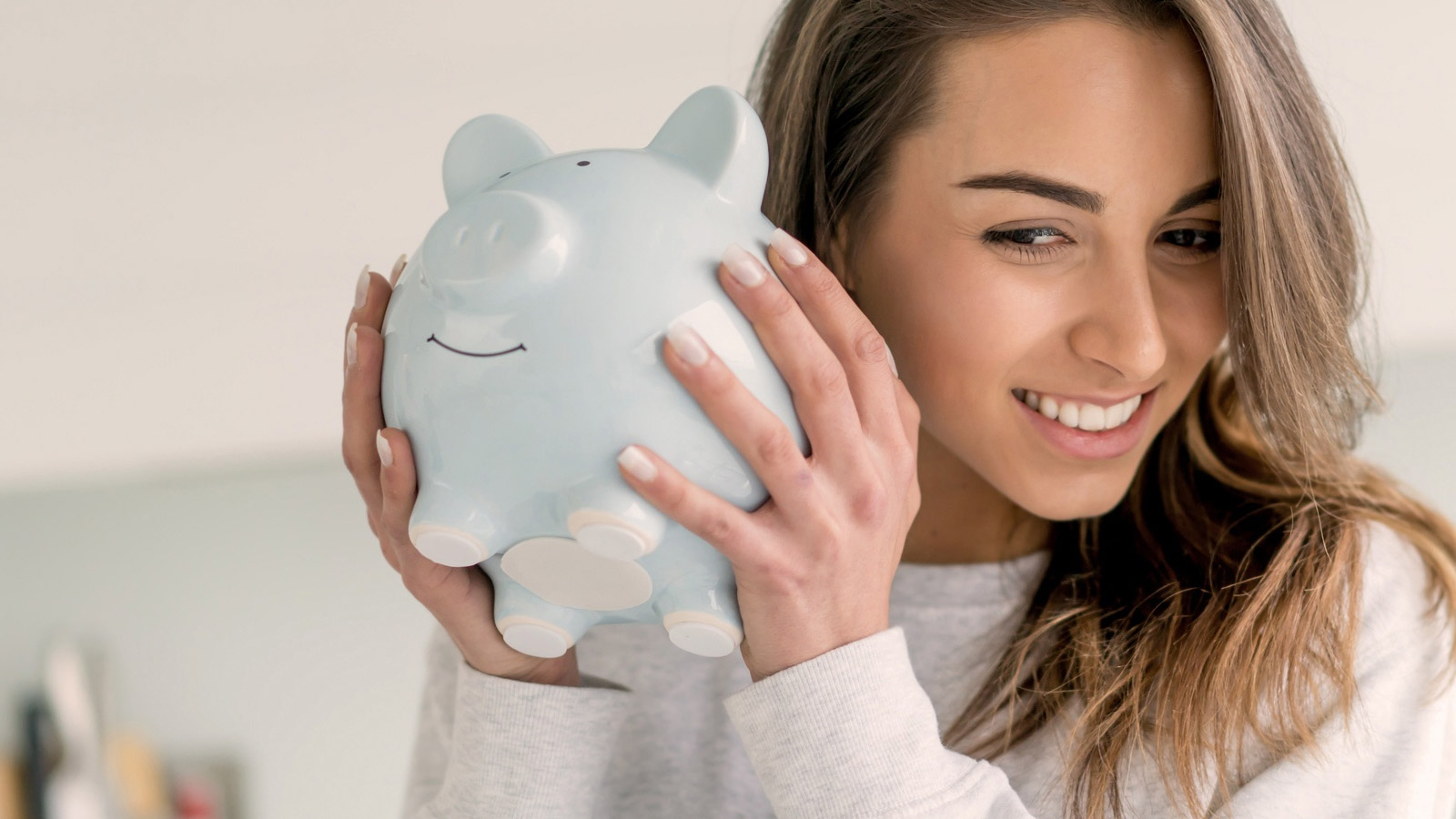 Eine Frau hält ein Sparschwein in der Hand.