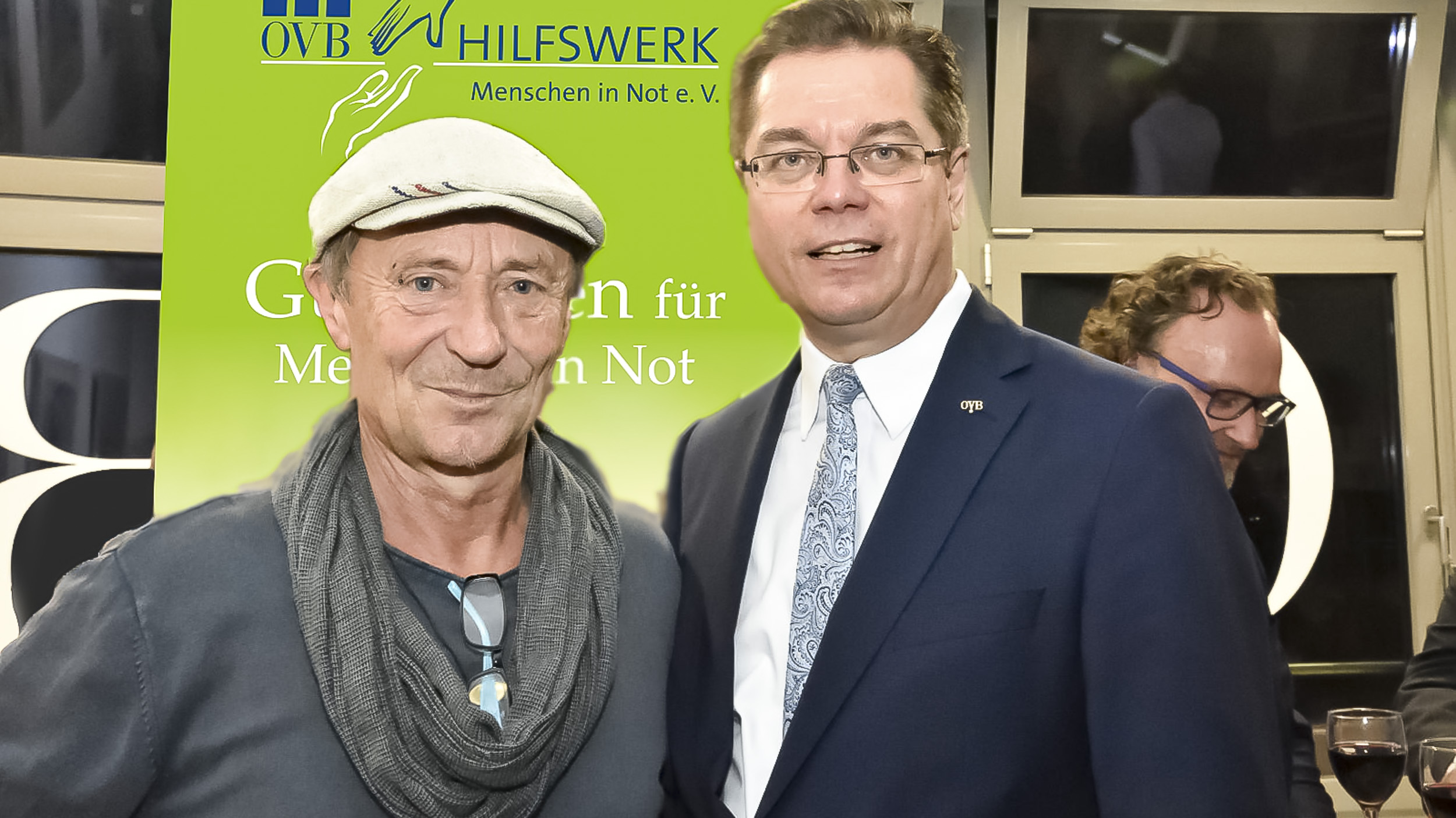 Der Leiter der Bahnhofsmission am Berliner Zoo Dieter Puhl steht mit Kappe auf links. Rechts steht Rolf Butschkat, Landesdirektor für die OVB Vermögensberatung AG in Berlin, im dunklen Anzug und Krawatte 