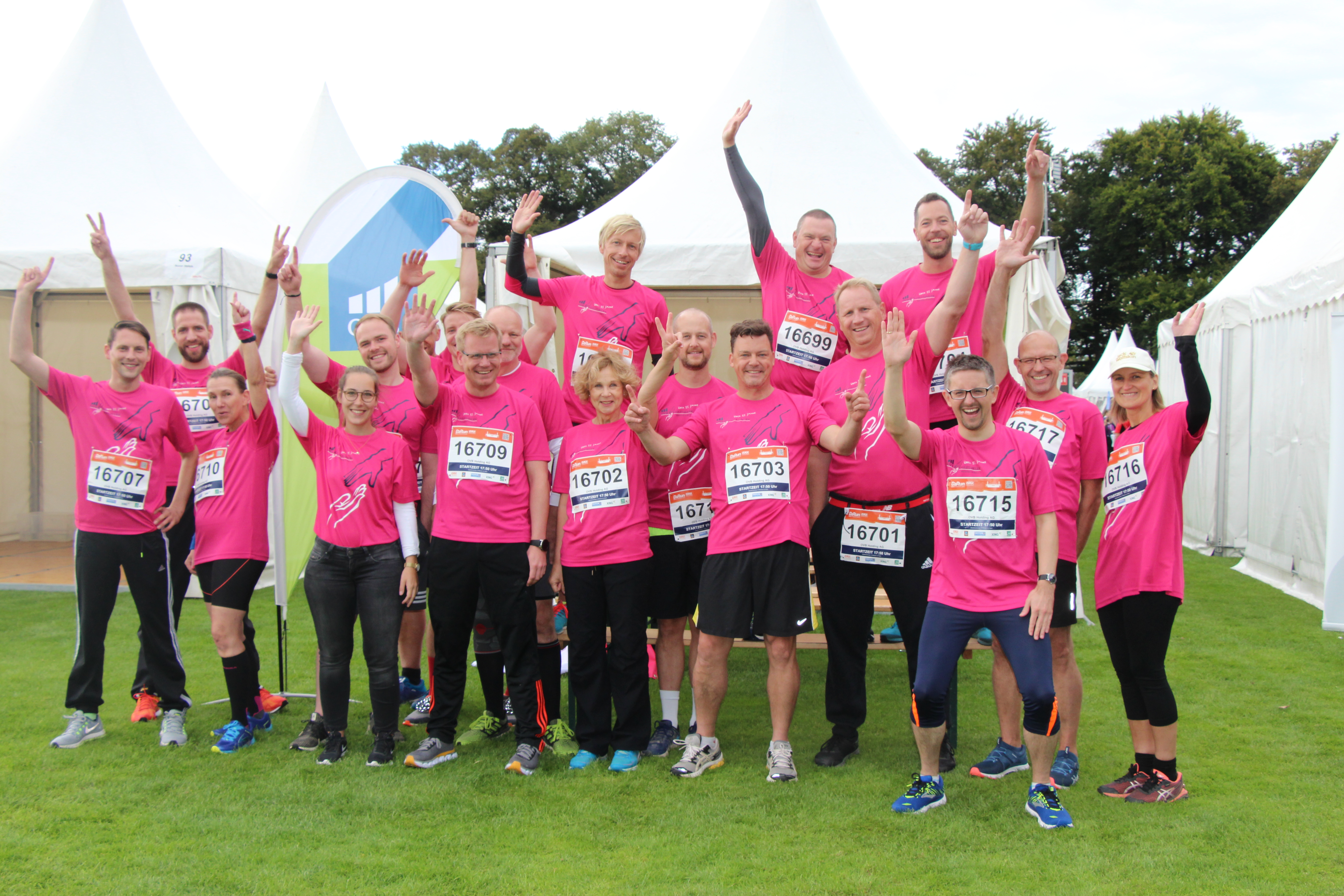 18 Menschen posieren auf Wiese in Rosa Trikots für den B2Run Benefizlauf