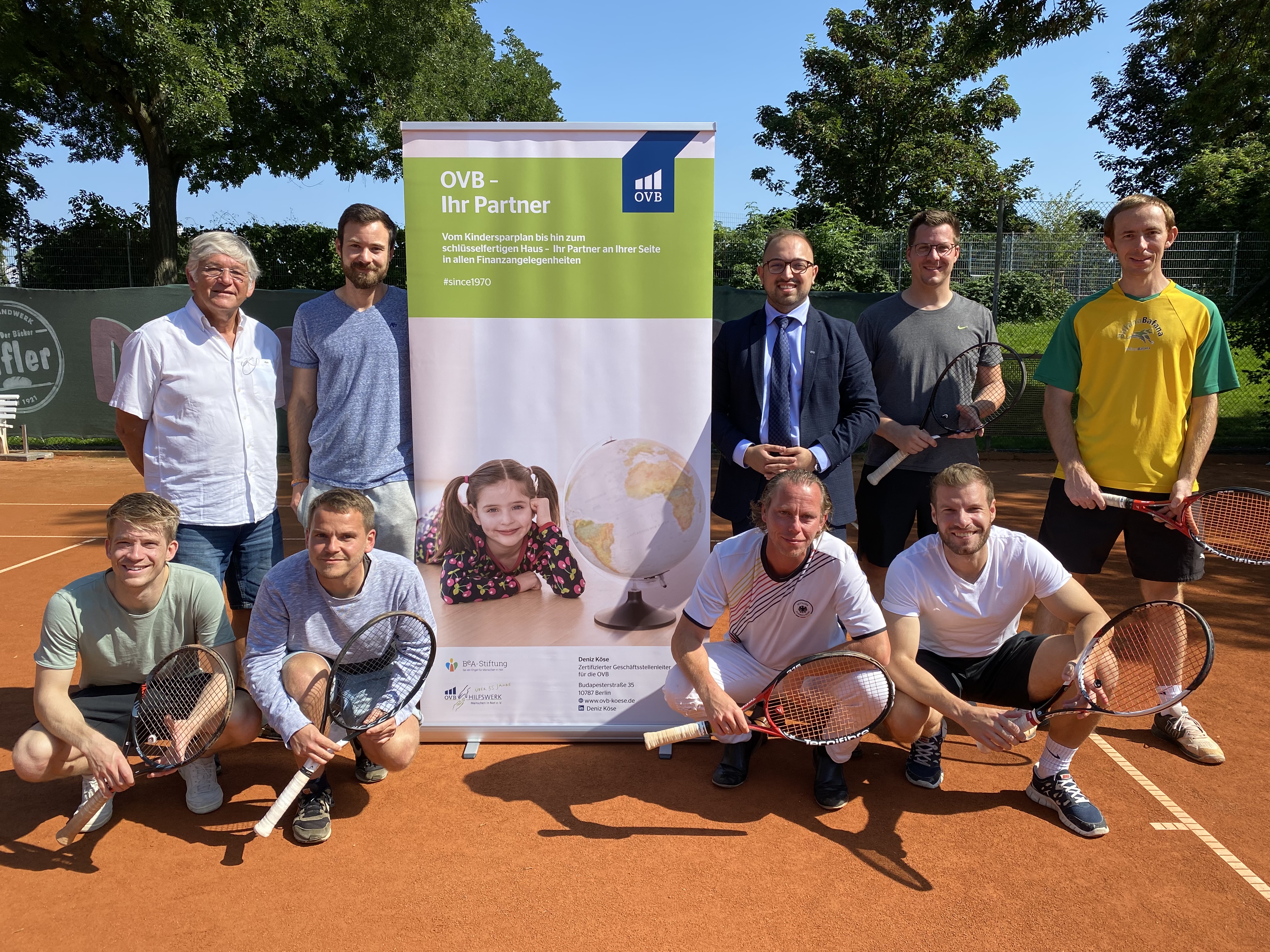 Deniz Köse und sein Team bei der sozialen Initiative des TC Bierstadt Tennisclubs. 9 Männer mit Tennisschläger auf dem Tennisplatz.
