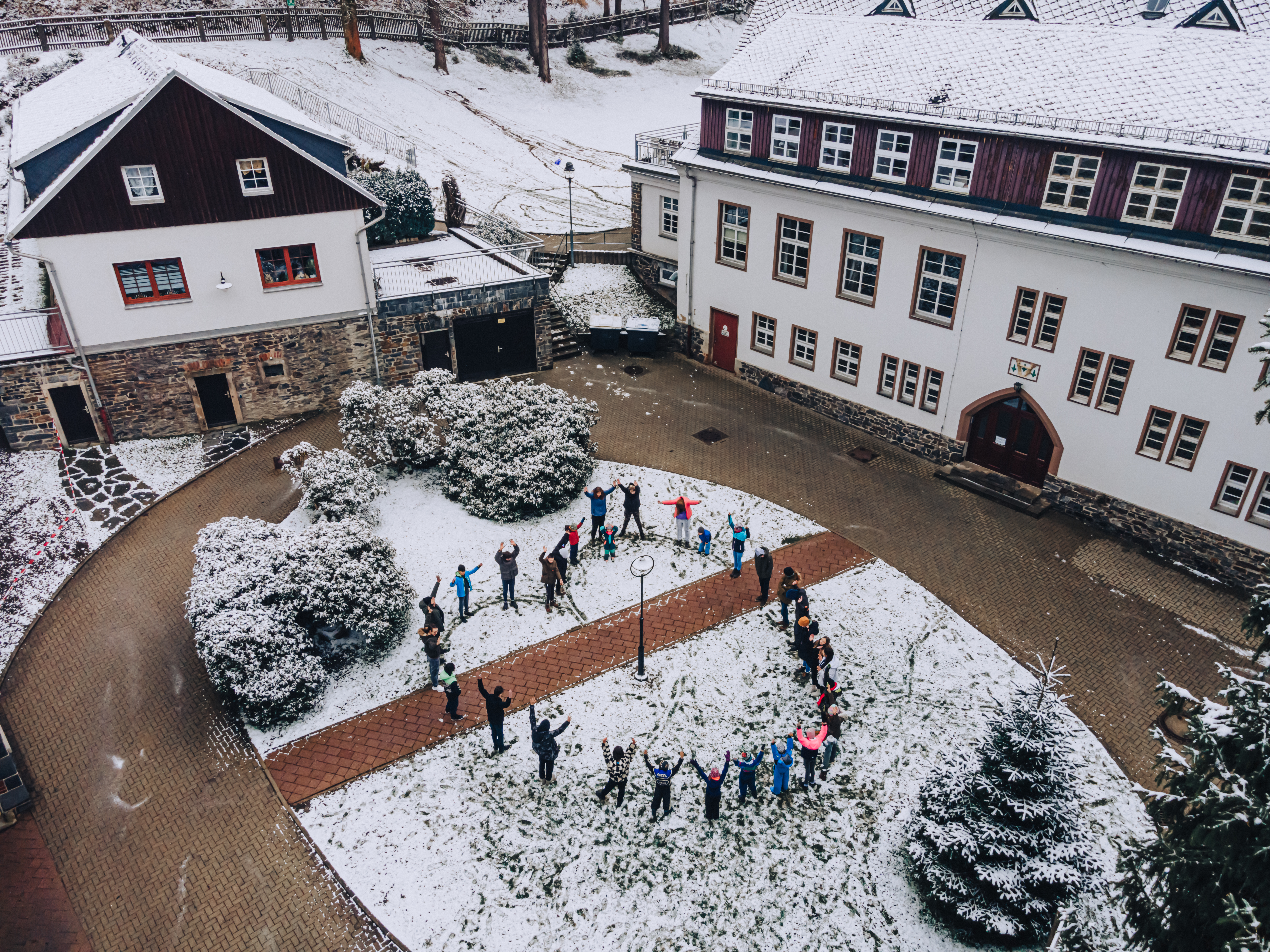 Kinder- und Jugendwohnen Tannenmühle aus der Vogelperspektive. Bewohner formen im Hof ein großes Herz als Menschenkette.