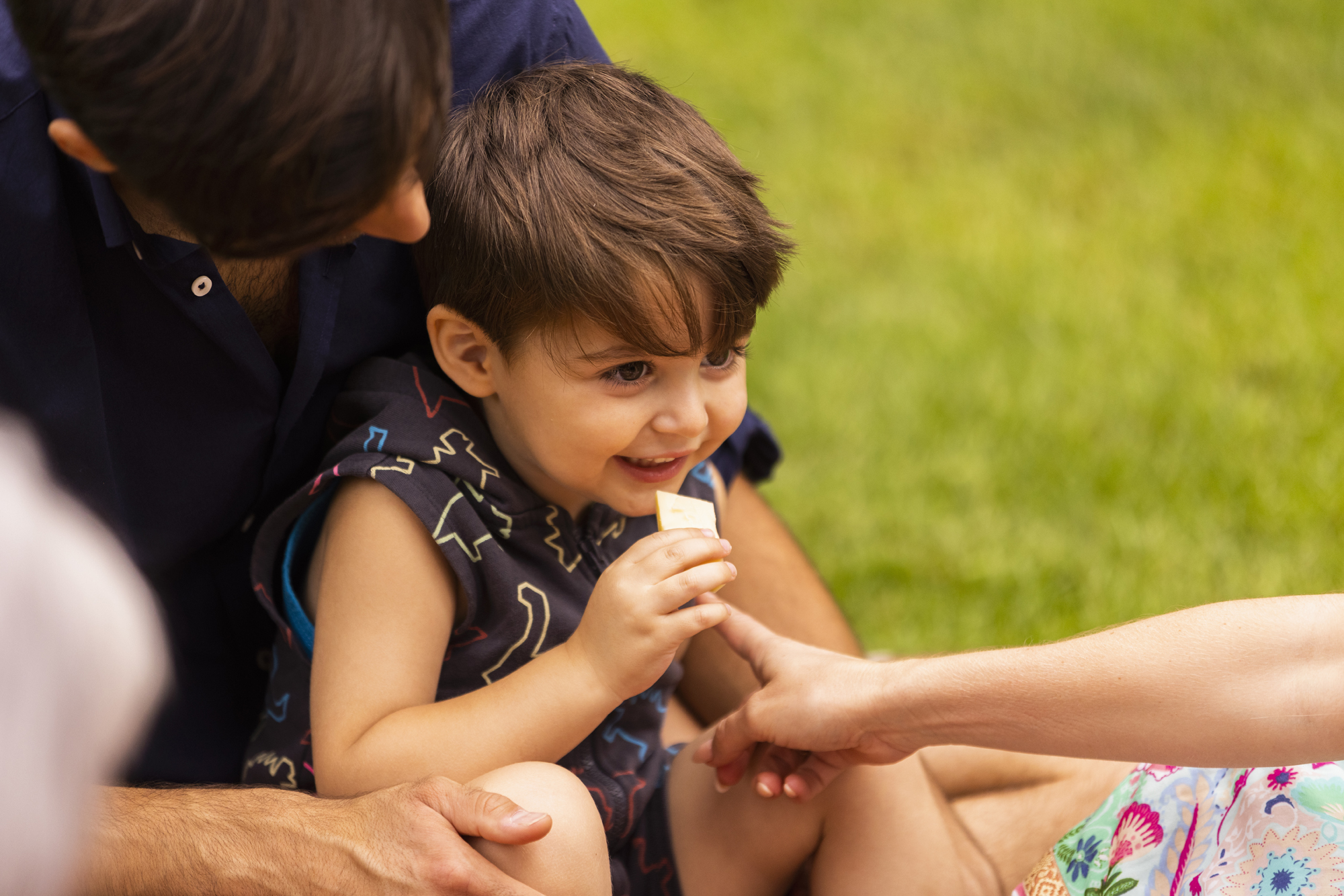 Kleinkind mit Süßigkeit in der Hand im Schoß seiner Mutter