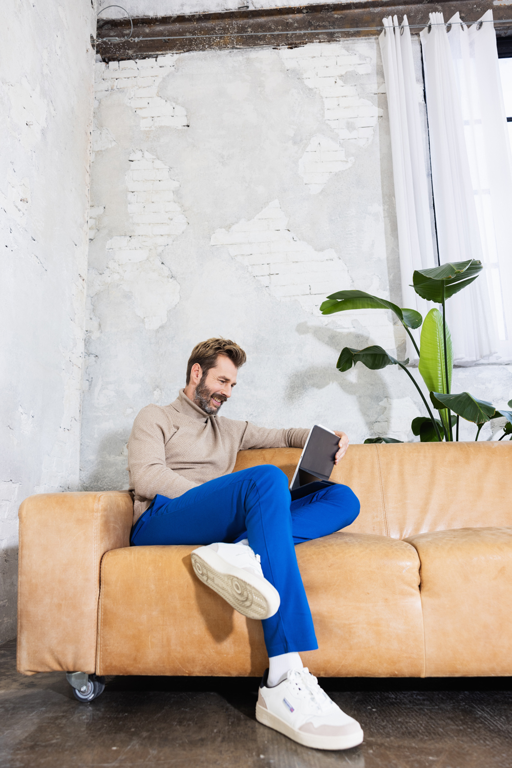 Mann sitzt mit Laptop auf dem Sofa